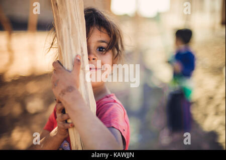 La ragazza si nasconde dietro un palo di legno Foto Stock