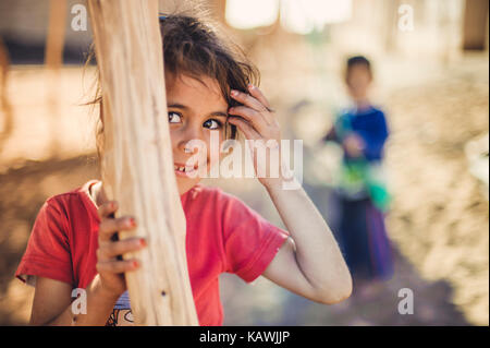 La ragazza si nasconde dietro un palo di legno Foto Stock