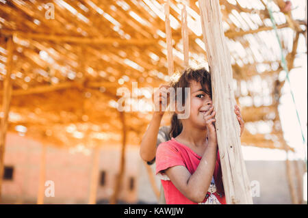 La ragazza si nasconde dietro un palo di legno Foto Stock