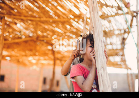 La ragazza si nasconde dietro un palo di legno Foto Stock