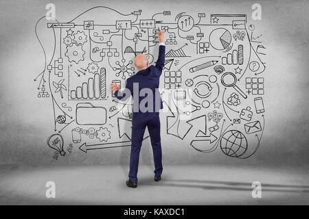 Vista di un imprenditore disegno disegnato a mano lo schema complesso su una parete - rete e concetto di comunicazione Foto Stock