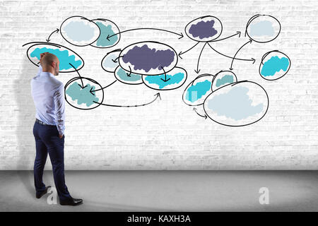Vista di un imprenditore di fronte un muro guardando un grafico di business organisation - concetto di business Foto Stock