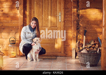 Ragazza carina con un bellissimo cane nella parte anteriore della casa in legno Foto Stock