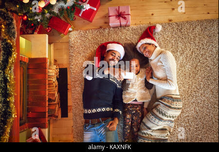 Mezza- cast famiglia far Natale selfie in posizione sdraiata Foto Stock