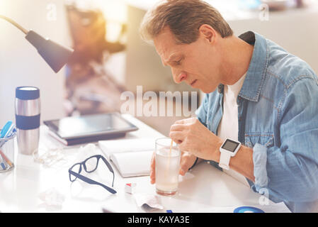 Cupa uomo maturo medicine di dissoluzione in acqua calda Foto Stock