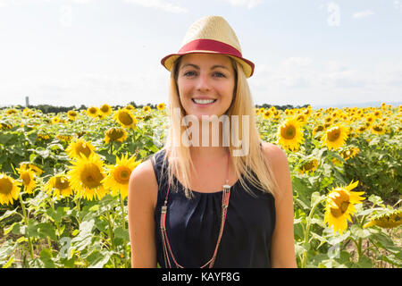 Donna con cappello sul campo di girasoli al tramonto Foto Stock