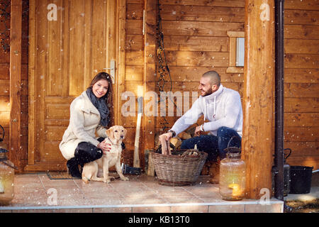 Coppia giovane la preparazione di legna da ardere in parte anteriore del week-end house Foto Stock