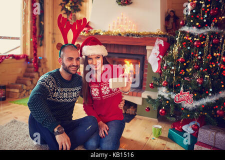 Ragazza ragazzo e rendere divertente selfie per natale all'interno Foto Stock