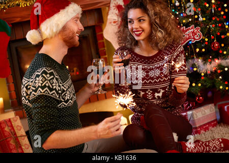 Coppia giovane per celebrare il Natale con il vino e bagliori Foto Stock