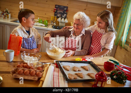 Nonna godendo con i nipoti la preparazione di biscotti di Natale a casa Foto Stock