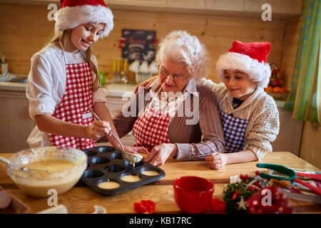 Nonna e nipoti la preparazione di biscotti di Natale - tempo per la famiglia Foto Stock