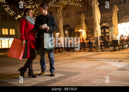 I giovani allegri facendo shopping di Natale in piedi sulla strada decorata Foto Stock