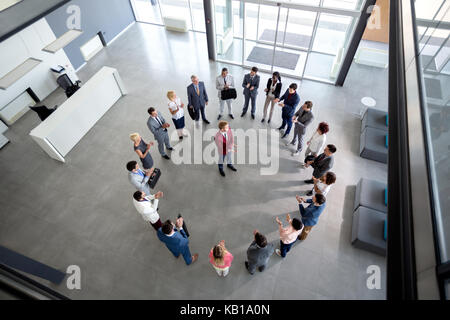 Vista superiore del team soddisfatti battendo le mani con manager nel centro del cerchio Foto Stock