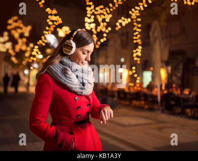 Donna che guarda il suo orologio in strada mentre aspetta il suo ragazzo che è in ritardo per una data Foto Stock