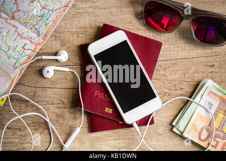 Preparazione per il viaggio, telefono cellulare, denaro, passaporto, road map sul tavolo di legno Foto Stock