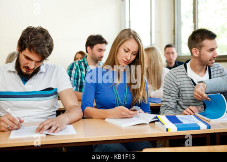 I giovani studenti a prendere appunti in classe Foto Stock