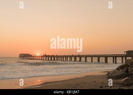 Silhouette del molo storico contro il sole di setting, a Swakopmund nel deserto del Namib sulla costa atlantica della Namibia Foto Stock