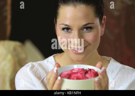 Bella giovane donna odori in fiori di rosa, aromaterapia, Foto Stock