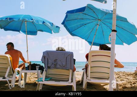 Luglio, 2017 - persone appoggiano sulle sedie a sdraio all'ombra di ombrelloni sulla spiaggia di cleopatra (Alanya, Turchia). Foto Stock