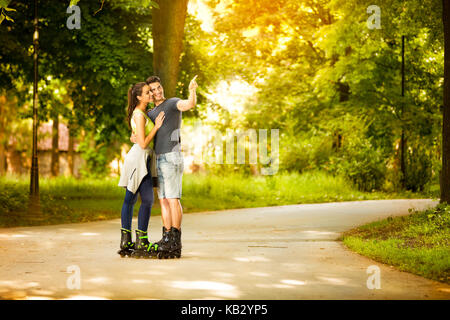 Amore coppia giovane con i pattini, giovane puntando con il dito Foto Stock