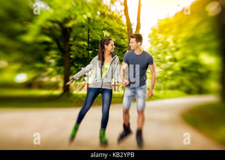 Giovani rullo felice coppia nel parco, tempo per pattini Foto Stock