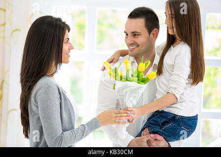 La famiglia felice sulla Giornata della madre, padre e figlia con fiori Foto Stock