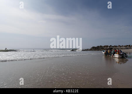 Un surfista cavalca l'onda come pescatore lanciare una barca presso la bamba spiaggia vicino a salina cruz, oaxaca, Messico. Foto Stock