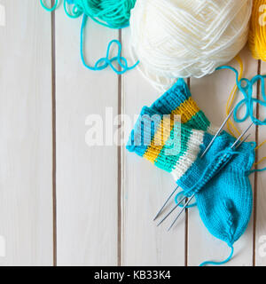 Una donna maglieria calze lavorate a maglia con bambini aghi di tessitura. strisce di turchese, giallo e bianco colori. Foto Stock