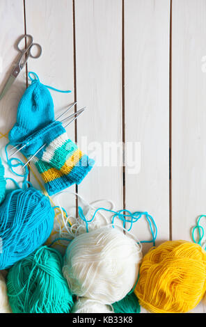 Una donna maglieria calze lavorate a maglia con bambini aghi di tessitura. strisce di turchese, giallo e bianco colori. Foto Stock