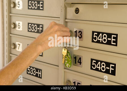 Caucasica Senior Female (età 60-70) apertura complesso di casella postale con chiave, Stati Uniti Foto Stock