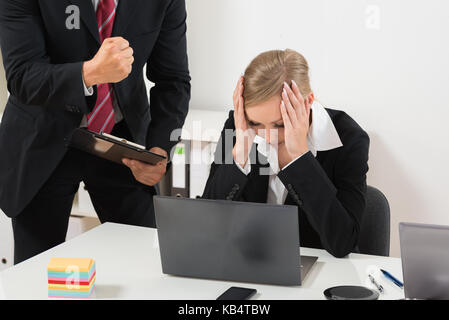 Boss con appunti di biasimare il dipendente di sesso femminile per i cattivi risultati Foto Stock