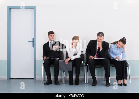 Gli imprenditori seduti su una sedia in attesa per il colloquio di lavoro in ufficio Foto Stock