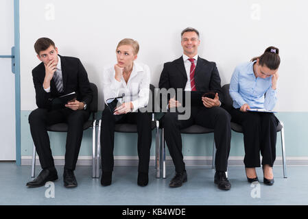 Gli imprenditori seduti su una sedia in attesa per il colloquio di lavoro in ufficio Foto Stock