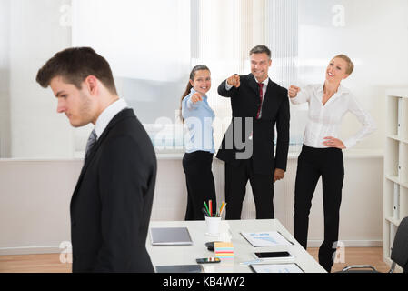 Happy businessman teasing giovane imprenditore da solo in ufficio Foto Stock