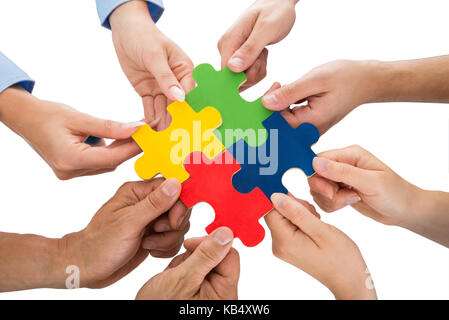 Close-up di persone mani collegando insieme pezzi di puzzle Foto Stock