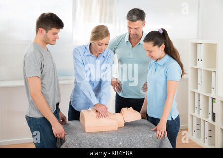 Gruppo di studenti imparare la rianimazione cardiopolmonare in classe Foto Stock