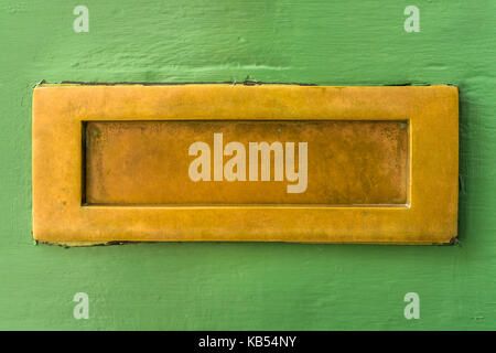 Un ben utilizzato ottone opache letterbox su un grosso modo verniciato di verde porta anteriore nel Regno Unito. Foto Stock