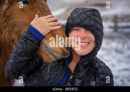 Donna con cavallo islandese in una tempesta di neve, Islanda Foto Stock