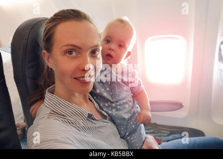 La madre e il bambino che viaggiano sul piano guarda la fotocamera Foto Stock