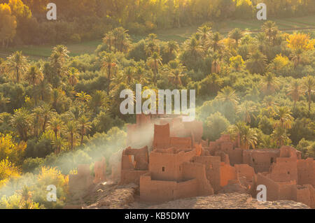 Rovinato kasbah nella Palmerie vicino a tinerhir, con fumo dal fuoco di vorticazione tramite gli alberi di palme, Marocco, Africa settentrionale, Africa Foto Stock