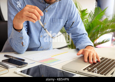 L'uomo studiando un report di analisi in un ufficio sfondo Foto Stock