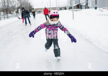 Bambina godendo di pattinaggio su ghiaccio nella stagione invernale Foto Stock