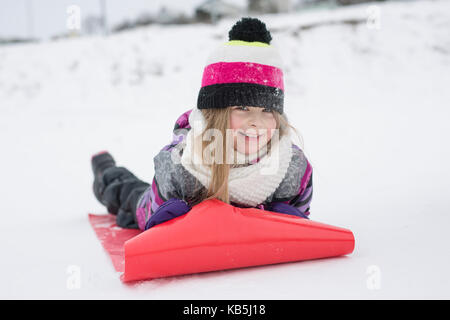 Bambina correre sulla neve slitte in inverno Foto Stock