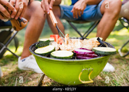 Irriconoscibile adolescenti Cucina verdure su barbecue grill. Foto Stock