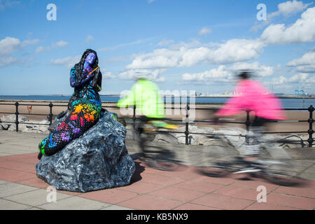 Il Wirral, Wallasey. Regno Unito Meteo. Il 28 settembre 2017. Giornata di sole a New Brighton come persone passeggiare in bicicletta lungo il lungomare di Marine, in condizioni di luce solare intensa. Il sentiero delle sirene mesmeric è ispirato alla Black Rock Mermaid, che è detto per avere sembrava un marinaio in New Brighton nel XVIII secolo. Queste creazioni colorate compongono il Mermaid Trail e hanno fatto il loro debutto nella cittadina balneare di accogliere i visitatori estivi. Credito; Credito: MediaWorldImages/Alamy Live News Foto Stock