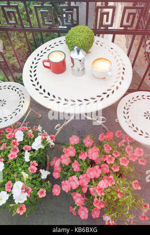 Tazze da caffè sul tavolo bianco sul balcone all'aperto Foto Stock