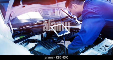 Mechanic utilizzando tablet per fissare auto presso il garage di riparazione Foto Stock