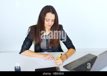 Ritratto di giovane sorridente business donna alla scrivania in ufficio la scrittura isolati su sfondo bianco Foto Stock