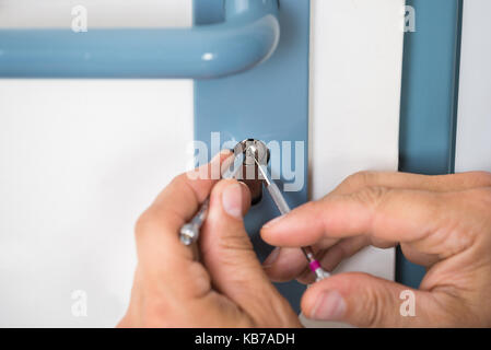 Immagine ritagliata di fissaggio lockpicker maniglia della porta a casa Foto Stock
