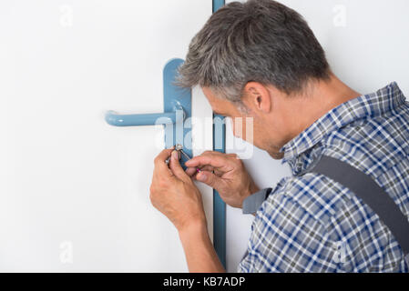 Immagine ritagliata di fissaggio lockpicker maniglia della porta a casa Foto Stock